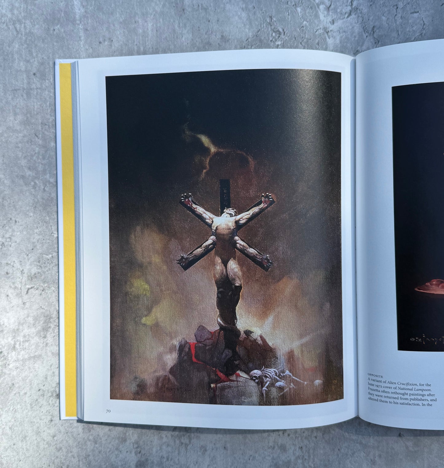 Open book on a textured surface with a photograph of Frank Frazetta artwork. 