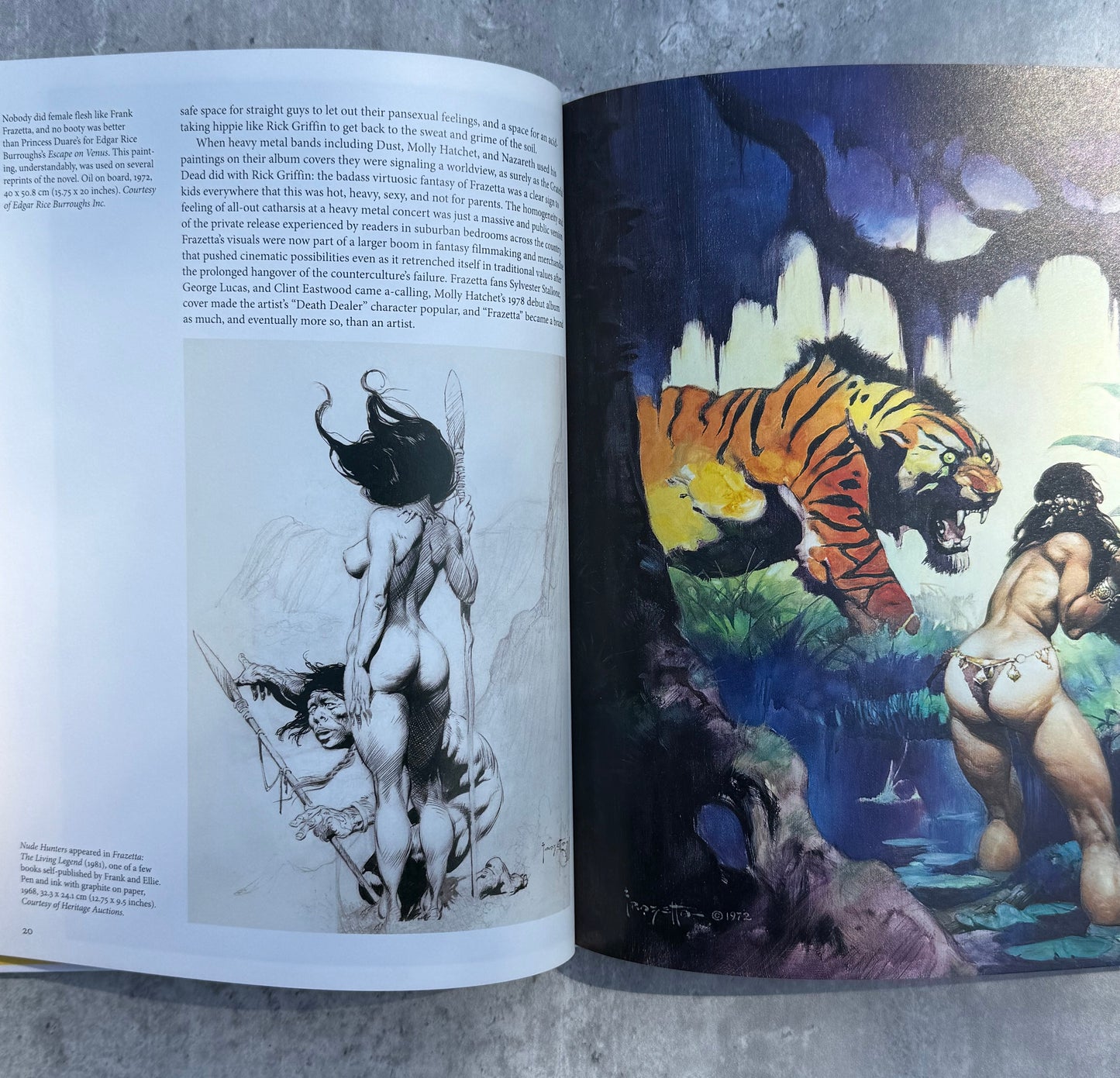 Open book with illustrations of a tiger and a woman on a gray surface, painting by Frank Frazetta.