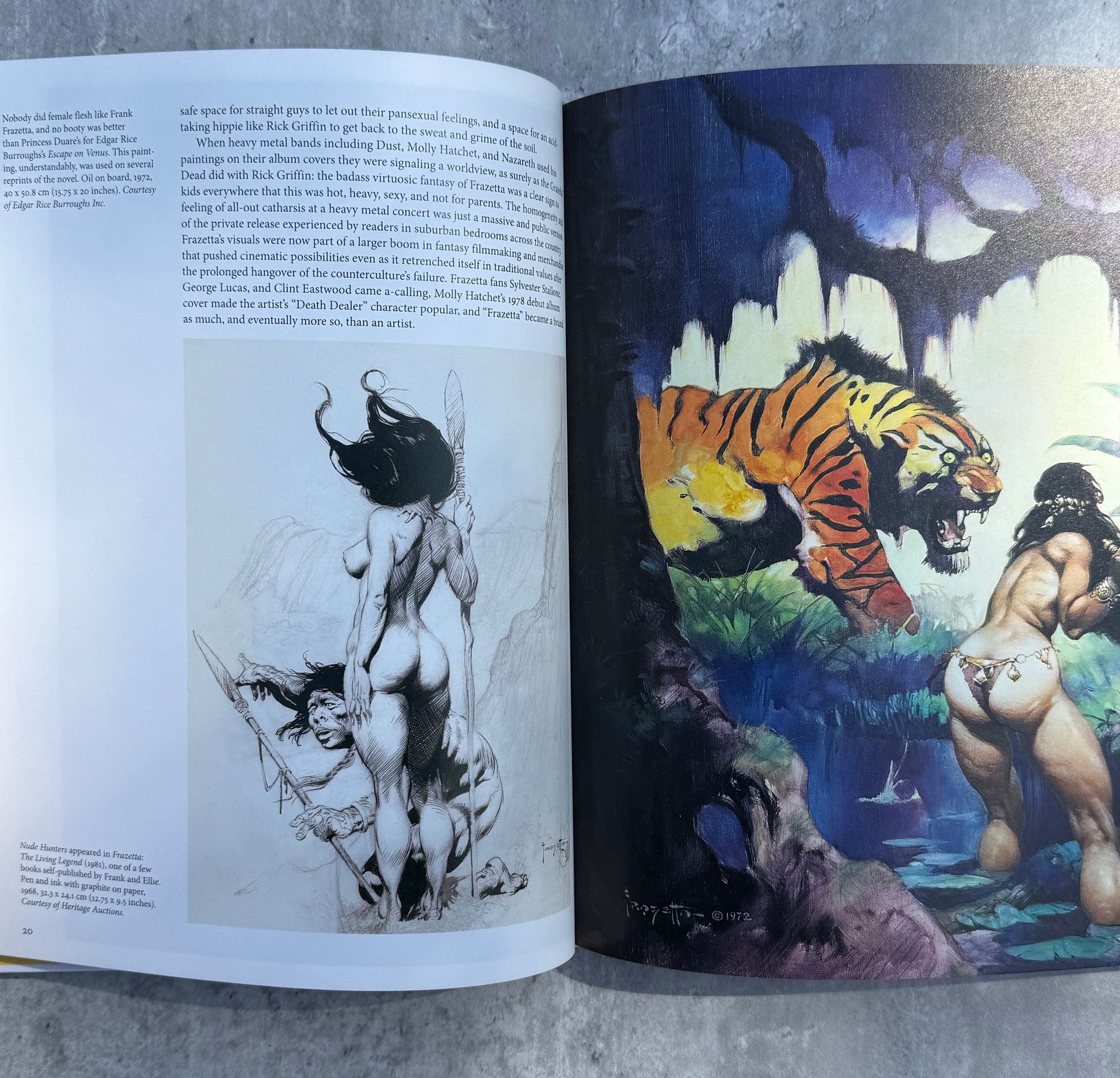 Open book with illustrations of a tiger and a woman on a gray surface, painting by Frank Frazetta.
