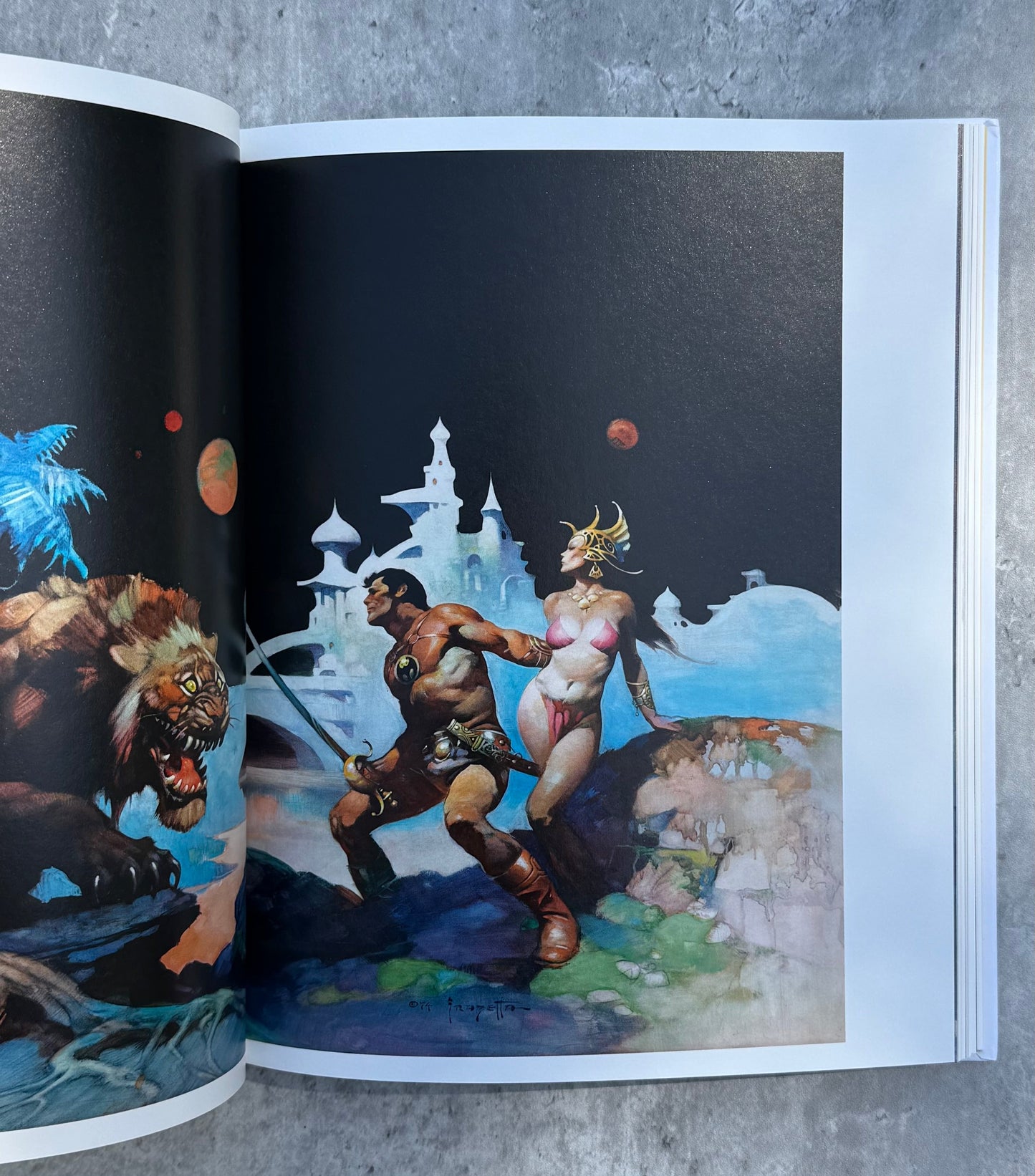Open book showing fantasy artwork of characters by Frank Frazetta. 